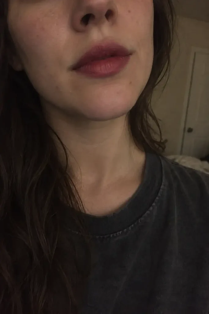 Close-up of muted berry lipstick with softly blended edges and visible lip lines in dim indoor light.